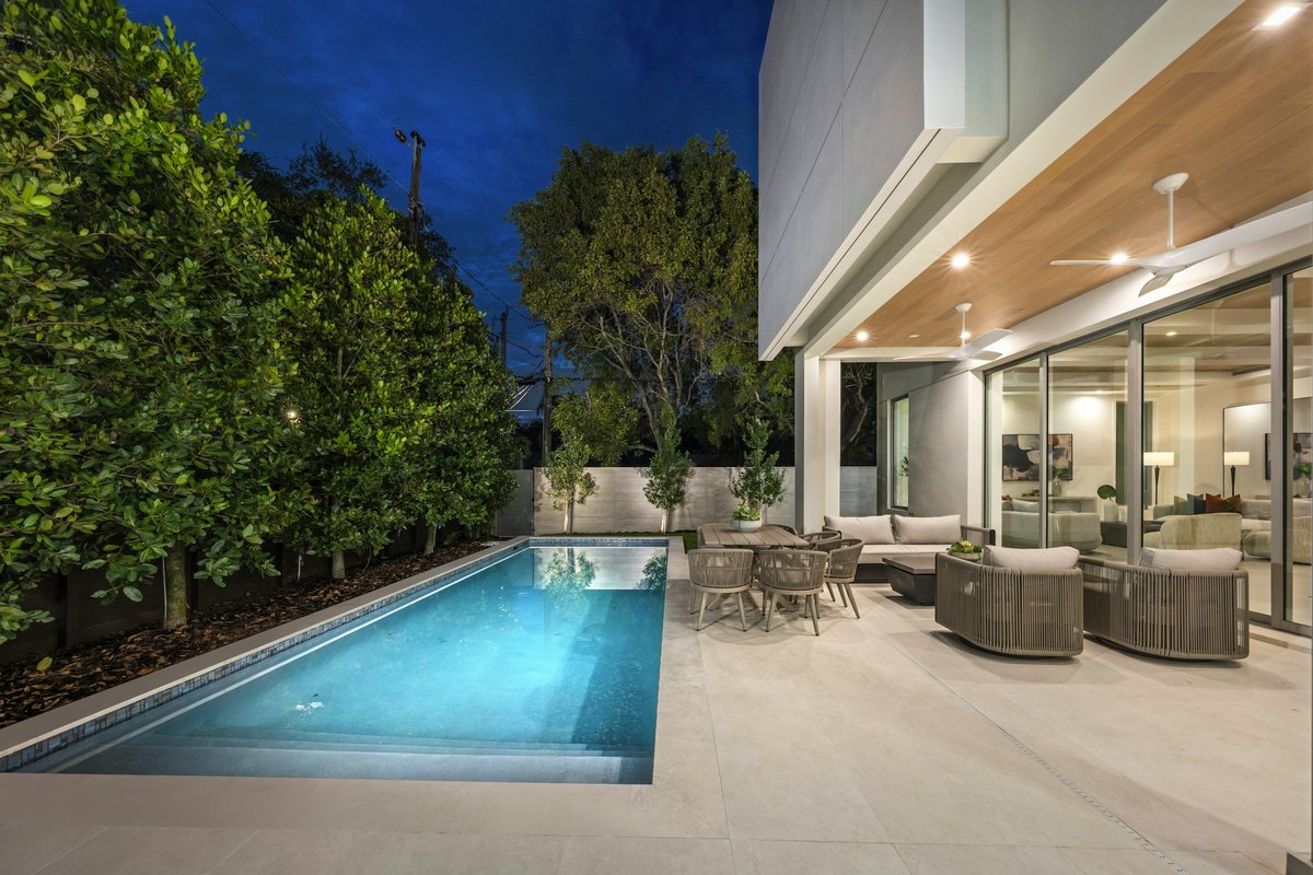 Pool and terrace lit at blue hour with the house glowing behind